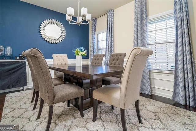 dining area with a chandelier, wood finished floors, and wainscoting