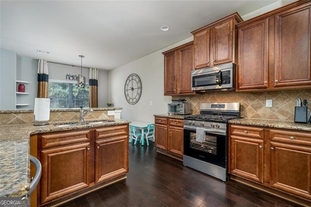 kitchen with a sink, backsplash, light stone counters, stainless steel appliances, and dark wood-style flooring