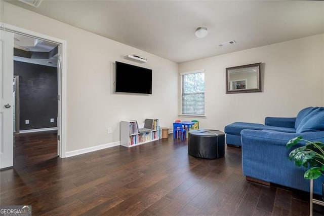 living room featuring visible vents, baseboards, and wood finished floors