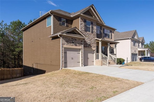 view of front of home with stone siding, an attached garage, driveway, and a front yard