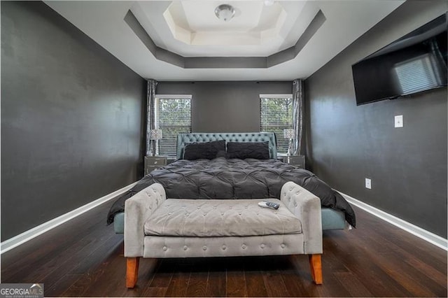 bedroom with a raised ceiling, hardwood / wood-style flooring, and baseboards