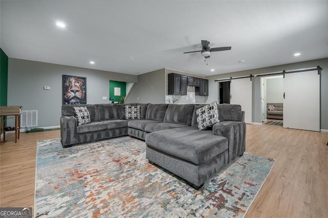 living area with visible vents, a barn door, recessed lighting, light wood-style floors, and a ceiling fan