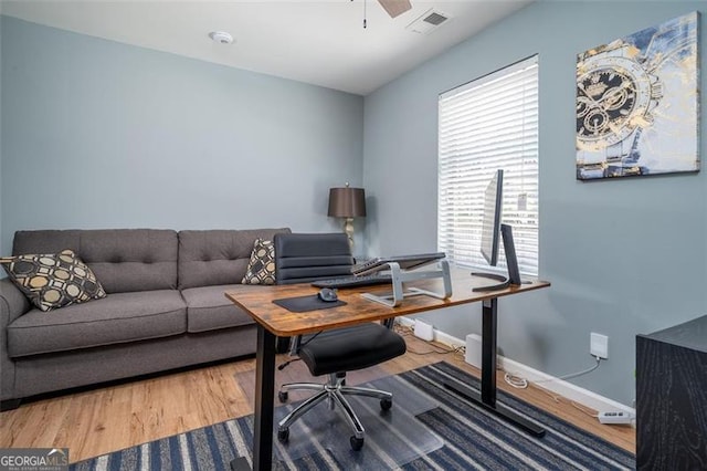 office area with a ceiling fan, visible vents, wood finished floors, and baseboards