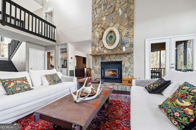 living room featuring stairway, a high ceiling, a fireplace, and french doors