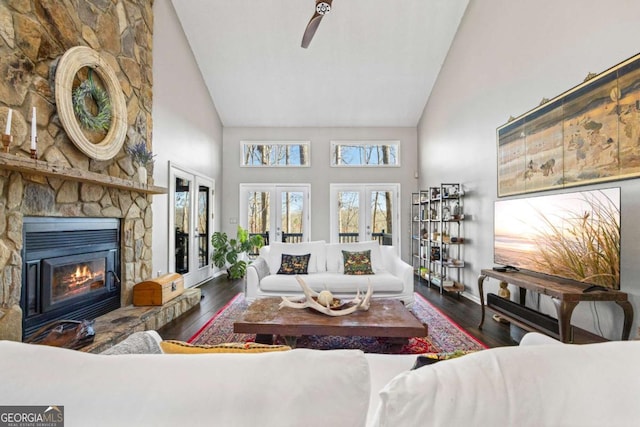 living area featuring a fireplace, wood finished floors, french doors, and high vaulted ceiling