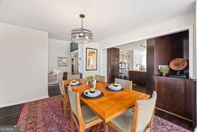 dining space featuring a textured ceiling, baseboards, and wood finished floors