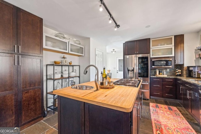 kitchen featuring backsplash, glass insert cabinets, appliances with stainless steel finishes, and wooden counters