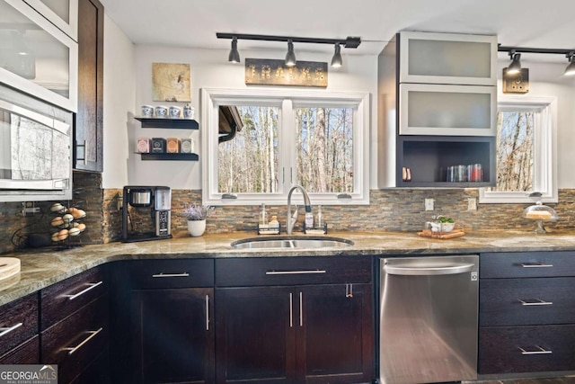 kitchen with stainless steel dishwasher, decorative backsplash, light stone countertops, and a sink