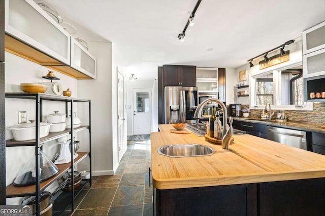 kitchen featuring stone tile floors, wooden counters, open shelves, a sink, and appliances with stainless steel finishes