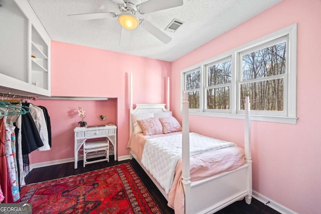 bedroom featuring visible vents, a ceiling fan, a textured ceiling, dark wood-style floors, and baseboards