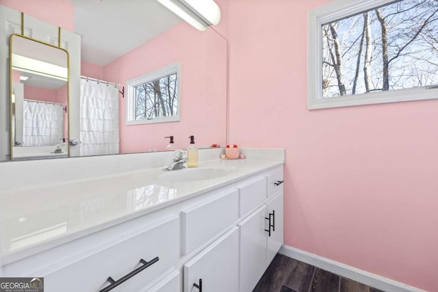 full bathroom featuring vanity, baseboards, and wood finished floors