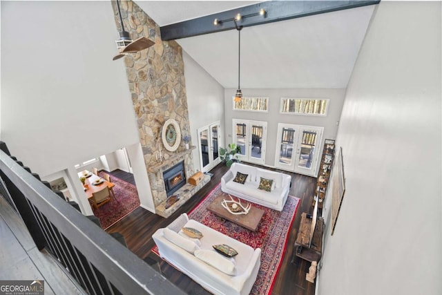 living room featuring beamed ceiling, a stone fireplace, french doors, wood finished floors, and high vaulted ceiling