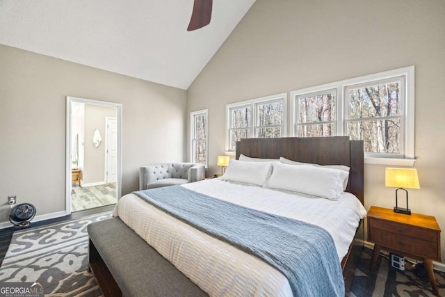 bedroom with a ceiling fan, wood finished floors, baseboards, high vaulted ceiling, and ensuite bathroom