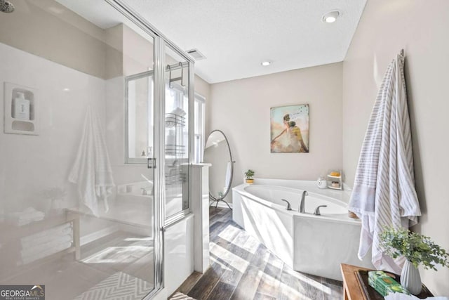 bathroom with wood finished floors, visible vents, a stall shower, a textured ceiling, and a bath