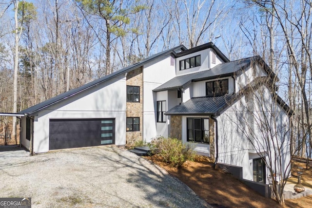 view of front of property featuring stone siding, an attached garage, metal roof, and driveway