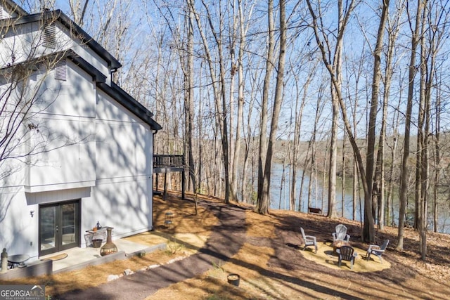 wooden deck featuring a fire pit, a water view, and french doors