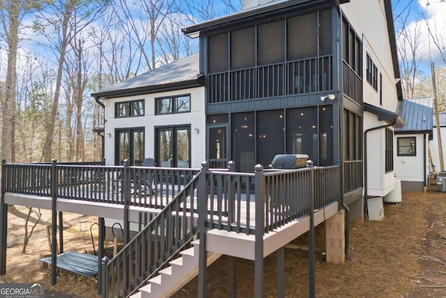 back of house featuring metal roof, stairs, a deck, and a sunroom