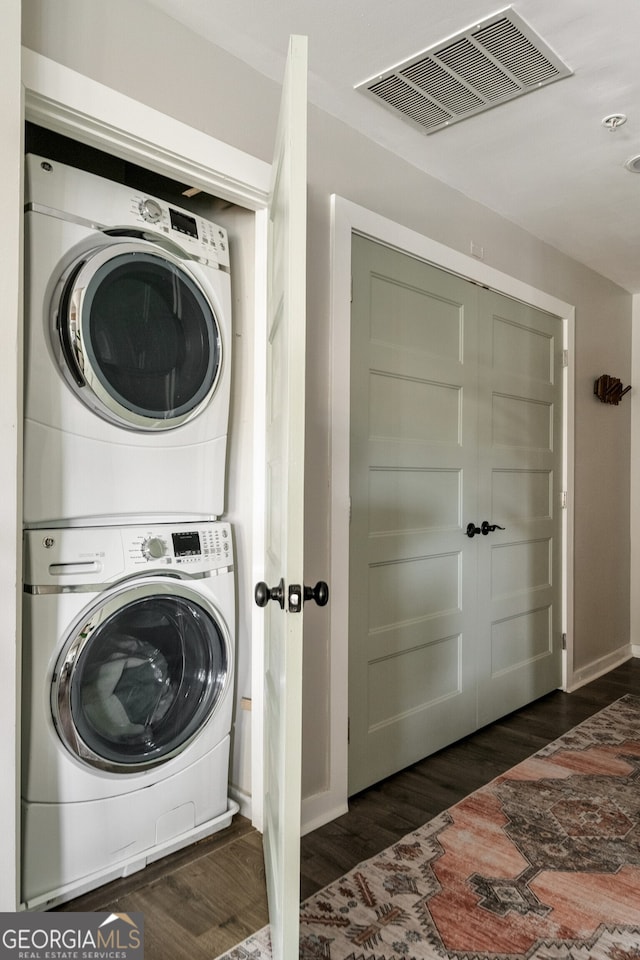 washroom featuring visible vents, wood finished floors, stacked washer / drying machine, and laundry area