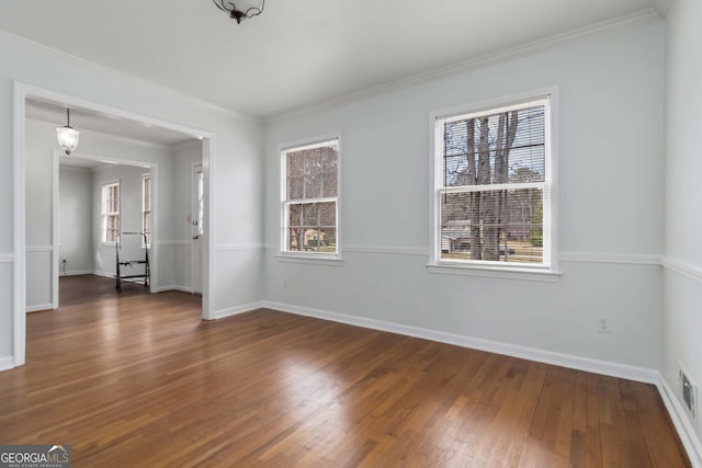 spare room featuring ornamental molding, baseboards, and wood finished floors