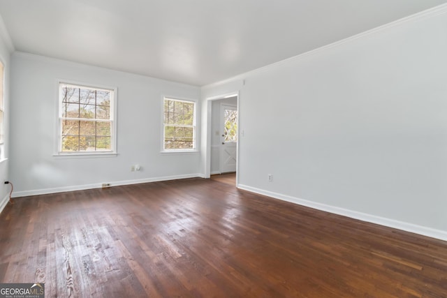 spare room featuring crown molding, dark wood-type flooring, and baseboards