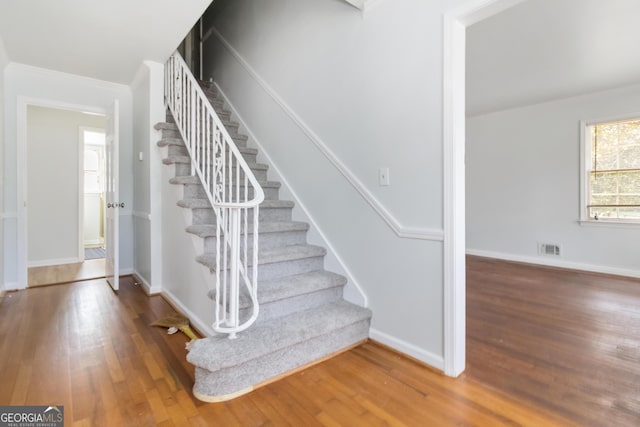 staircase with visible vents, baseboards, and hardwood / wood-style floors