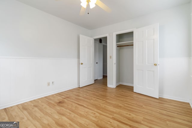 unfurnished bedroom with a ceiling fan, light wood-style floors, a wainscoted wall, and a closet