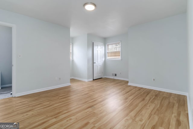 empty room featuring light wood finished floors, visible vents, and baseboards