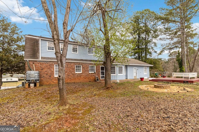 back of house featuring brick siding, a fire pit, and fence