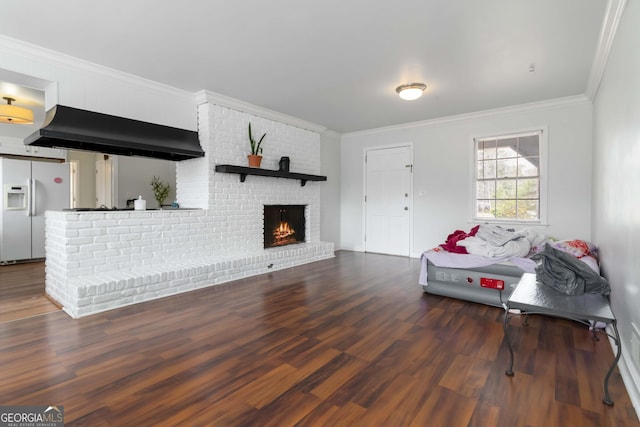 living room featuring a brick fireplace, crown molding, and wood finished floors