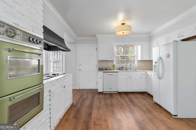 kitchen featuring a sink, white cabinetry, white appliances, wall chimney exhaust hood, and crown molding