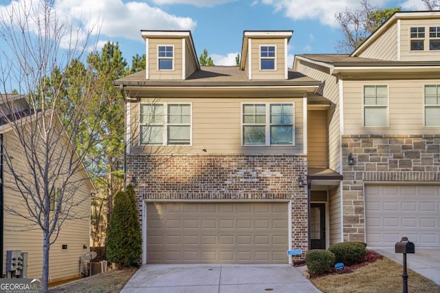 view of front facade featuring brick siding, stone siding, driveway, and an attached garage