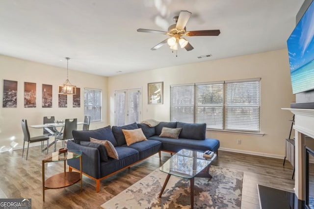 living area with a wealth of natural light, visible vents, a fireplace with flush hearth, and wood finished floors