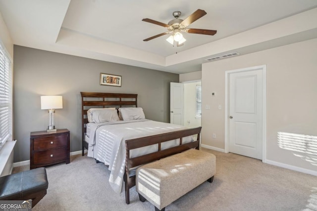 bedroom with visible vents, baseboards, a raised ceiling, light colored carpet, and ceiling fan