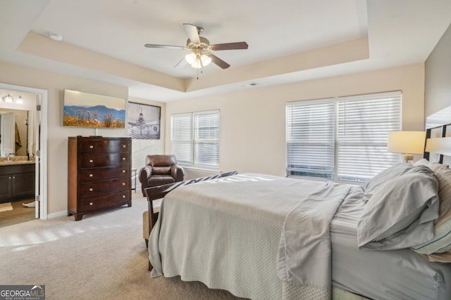 bedroom featuring light carpet, ceiling fan, baseboards, and a tray ceiling