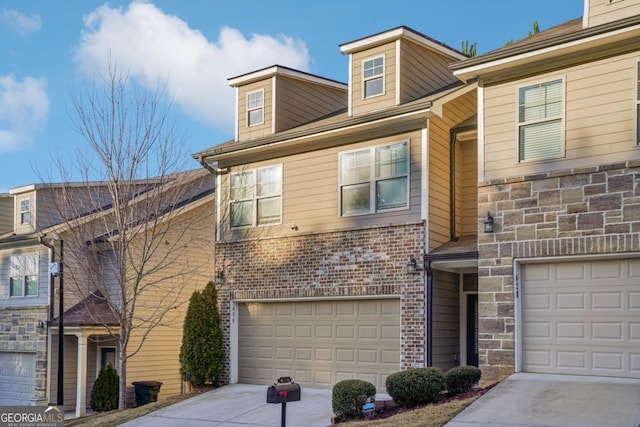 view of property featuring stone siding, an attached garage, brick siding, and driveway