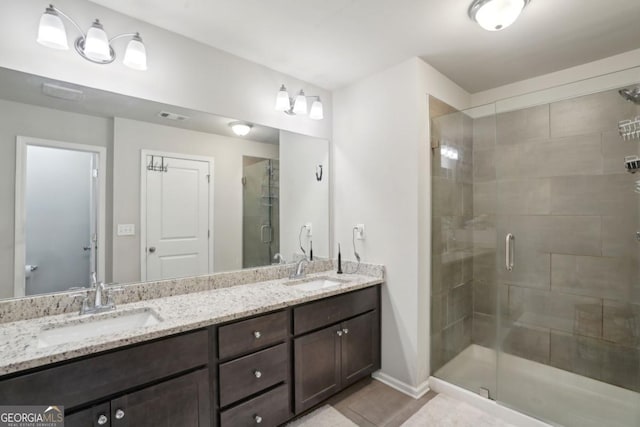 bathroom featuring a shower stall, double vanity, visible vents, and a sink