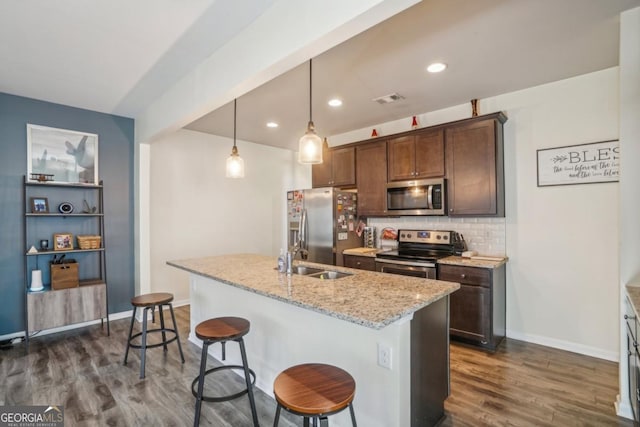 kitchen featuring a sink, appliances with stainless steel finishes, decorative backsplash, light stone countertops, and dark wood-style flooring