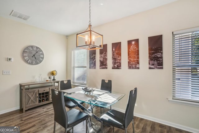 dining room with wood finished floors, visible vents, a chandelier, and baseboards