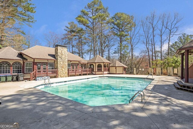 pool featuring a patio area, a wooden deck, and fence