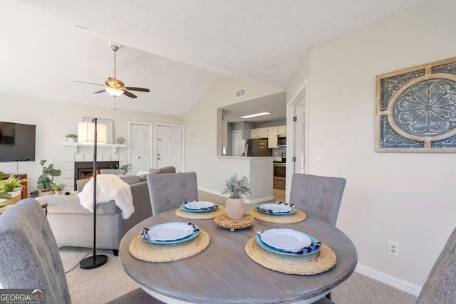 carpeted dining area featuring visible vents, baseboards, lofted ceiling, a fireplace, and ceiling fan