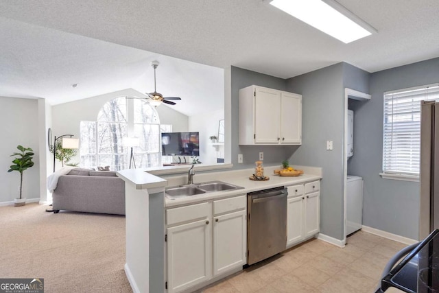 kitchen featuring open floor plan, a peninsula, stainless steel dishwasher, white cabinetry, and a sink