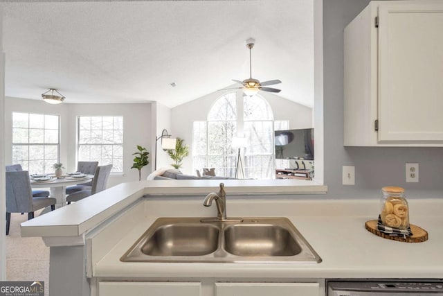 kitchen featuring white cabinetry, a sink, light countertops, dishwasher, and open floor plan