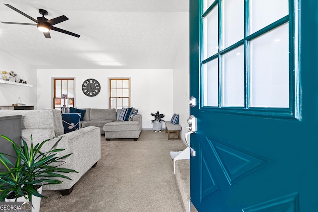 carpeted living area featuring ceiling fan and a textured ceiling