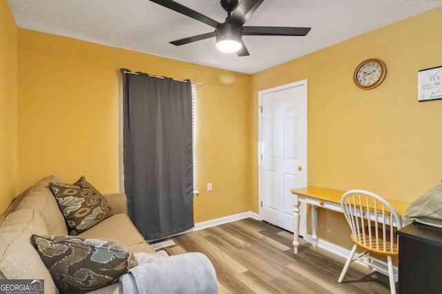 living area with ceiling fan, visible vents, baseboards, and wood finished floors