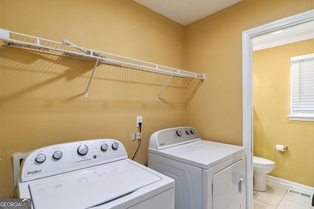 clothes washing area with washer and dryer, visible vents, baseboards, and light tile patterned floors