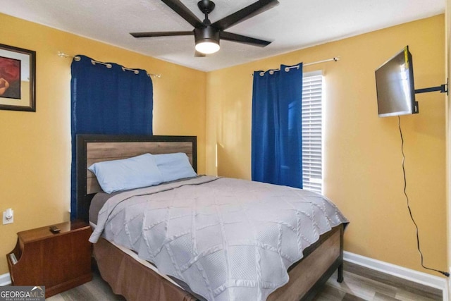 bedroom with a ceiling fan, wood finished floors, and baseboards