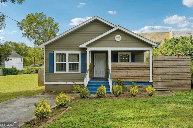 bungalow-style home featuring covered porch and a front lawn