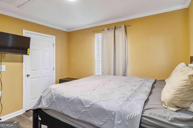 bedroom featuring crown molding, baseboards, and wood finished floors