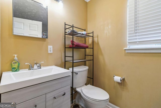 half bath featuring baseboards, toilet, and vanity