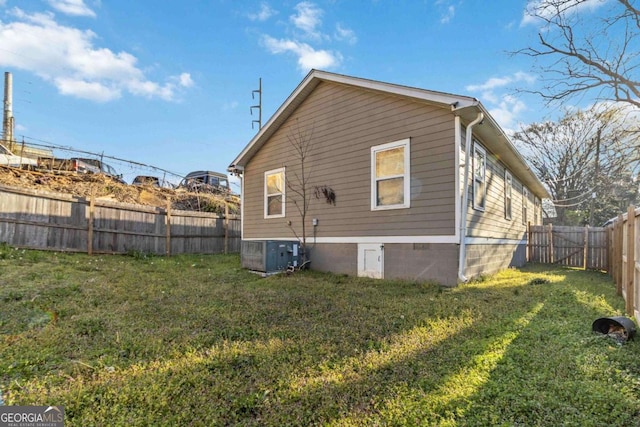 rear view of property with a yard, central AC, and a fenced backyard